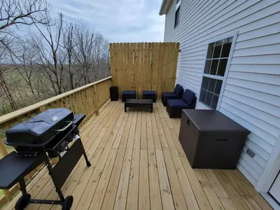 a patio with a grill and chairs on a deck at The Third Monkey in Williamstown