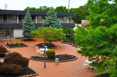 a courtyard with chairs and trees and a building at Avalon Inn in Sandusky
