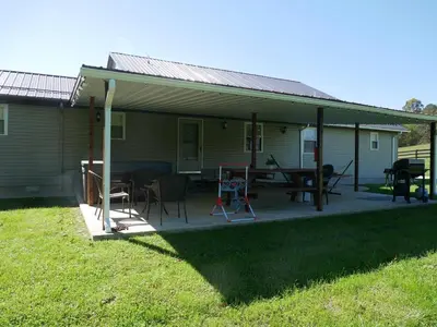 a covered porch of a house with a table and chairs at PineRidge Country Retreat with In ground Pool and Hot Tub in Langsville