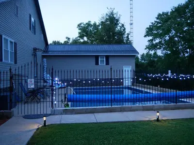 a fence in front of a house with a swimming pool at PineRidge Country Retreat with In ground Pool and Hot Tub in Langsville