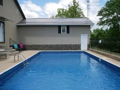 a swimming pool in front of a house at PineRidge Country Retreat with In ground Pool and Hot Tub in Langsville