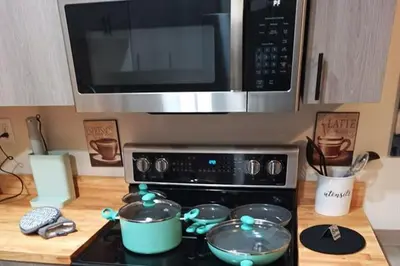 a kitchen with a stove with two pots and a microwave at Coastal Retreat in Sandusky
