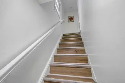 a staircase with white walls and wooden floors at New Renovated 1BR with King Modern Comfort in Berea