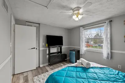 a bedroom with a blue bed and a flat screen tv at Cosy house, home away from home in Grove City