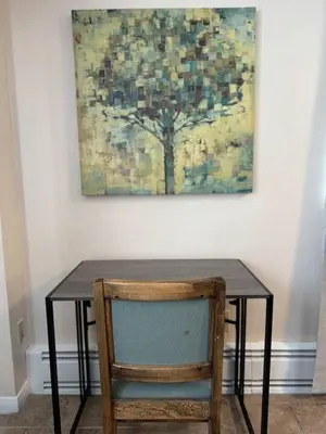 a table with a chair in front of a painting at Apt Near Oberlin College in Oberlin