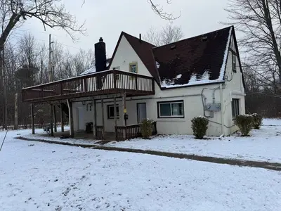 a white house with a deck in the snow at Apt Near Oberlin College in Oberlin