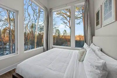 a bedroom with a white bed with large windows at Adamina Canyon Luxurious Villa with Wellness room 5 in Rockbridge