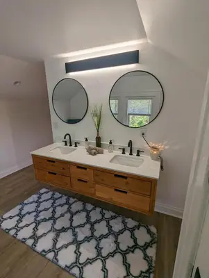 a bathroom with a sink and two mirrors and a rug at Bright Studio Stay Downtown in Columbus
