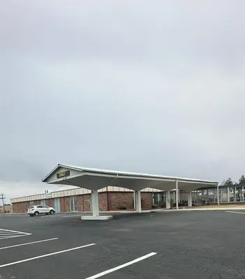 a building with a car parked in a parking lot at Napoleon Inn and Suites in Napoleon