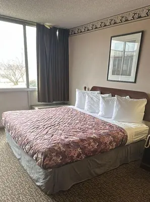 a hotel room with a large bed with white pillows at Napoleon Inn and Suites in Napoleon
