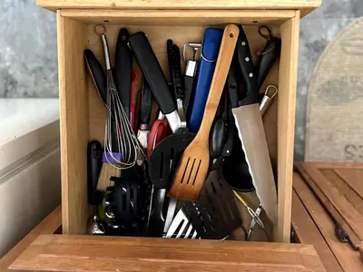 a wooden drawer filled with lots of cooking utensils at Rustic Cabin Rental near Akron, Ohio in Dellroy