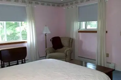 a bedroom with a bed and a chair and windows at Romantic Room Rental on a Lovely Farm near Hillsboro, Ohio