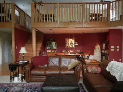 a living room with a leather couch and a staircase at Romantic Room Rental on a Lovely Farm near Hillsboro, Ohio