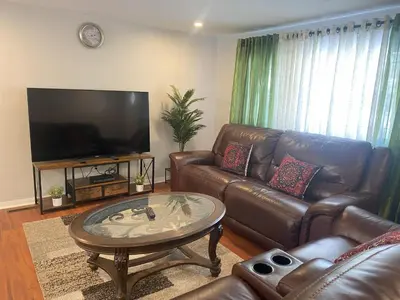 a living room with leather furniture and a flat screen tv at Bachome in Kettering