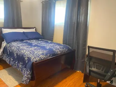 a bedroom with a bed with blue curtains and a television at Bachome in Kettering