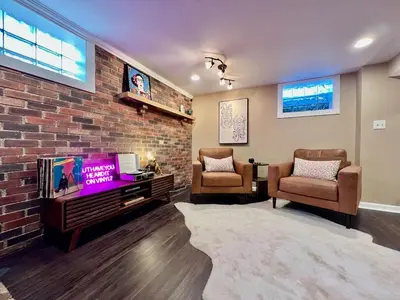 a living room with a tv and a brick wall at All the Vibes Poolside in Trenton in Trenton