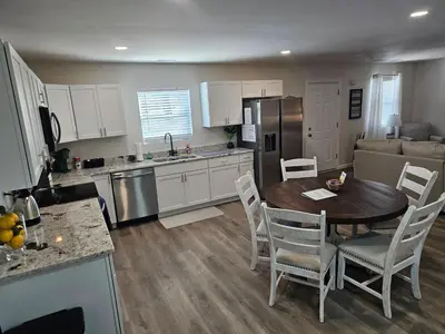 a kitchen and living room with a table and chairs at Cozy New Const. Ranch Near Park in Middletown