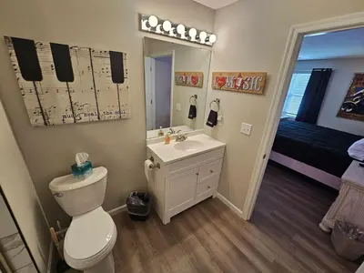 a bathroom with a toilet and a sink and a mirror at And . . . . the Beat Goes On in Trenton