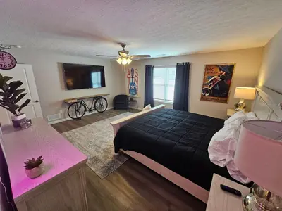 a bedroom with a black bed and a tv at And . . . . the Beat Goes On in Trenton