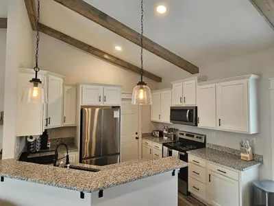a kitchen with white cabinets and a stainless steel refrigerator at Upscale New Construction Ranch in Middletown