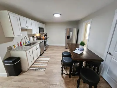 a kitchen with a wooden table and a kitchen with white cabinets at Quaint Liberty Township Remodeled Home in Hamilton