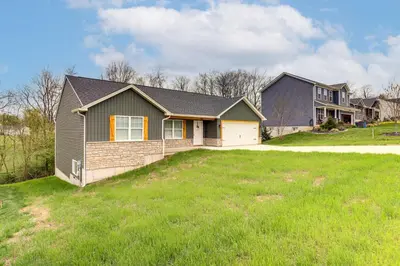 a house with a green lawn in front of it at 8 Mi to Ark Encounter Family Home with Deck and Grill in Dry Ridge