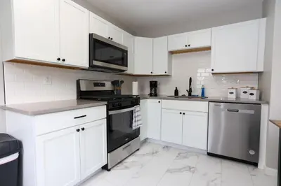 a white kitchen with black appliances and white cabinets at New Charloe Court 3 Bed Family House in Cincinnati