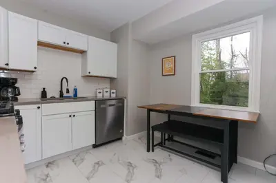 a kitchen with white cabinets and a table and a window at New Charloe Court 3 Bed Family House in Cincinnati