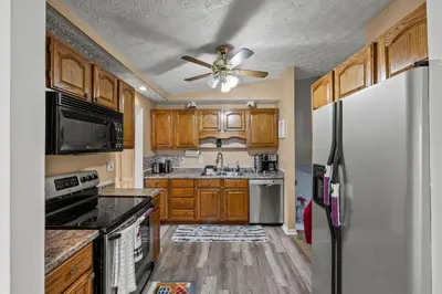 a kitchen with wooden cabinets and a ceiling fan at Cosy house, home away from home in Grove City