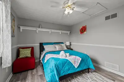 a bedroom with a blue bed and a red chair at Cosy house, home away from home in Grove City