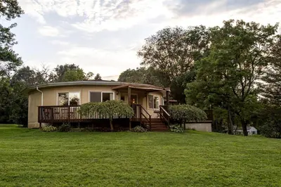 a small house on a grassy field with trees at Unique Ohio Cottage for a Weekend Getaway in the Midwest in Perrysville