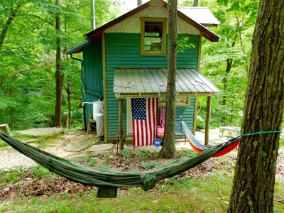 a hammock in front of a house with an american flag at Rustic Off-Grid Cabin Getaway near Wayne National Forest, Ohio in Athens