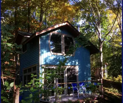 a blue tiny house in the middle of a forest at Rustic Off-Grid Cabin Getaway near Wayne National Forest, Ohio in Athens