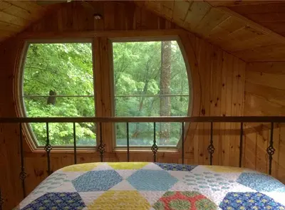 a bedroom with a quilt on a bed in front of a window at Rustic Off-Grid Cabin Getaway near Wayne National Forest, Ohio in Athens