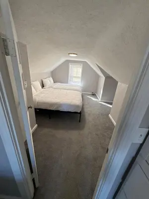 a small bedroom with a bed in a attic at Cozy Euclid Home Near Lakefront in Euclid