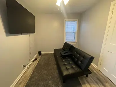a living room with a black leather couch and a window at Cozy Euclid Home Near Lakefront in Euclid