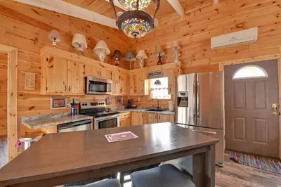 a kitchen with wooden cabinets and a stainless steel refrigerator at Bring a Pet Peaceful Frenchburg Cabin on 1 Acre in Frenchburg