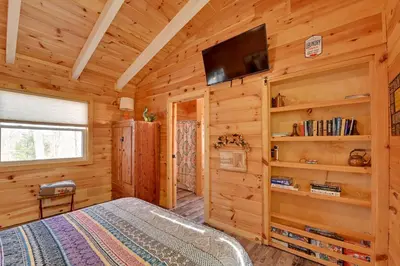 a log cabin bedroom with a bed and a flat screen tv at Bring a Pet Peaceful Frenchburg Cabin on 1 Acre in Frenchburg