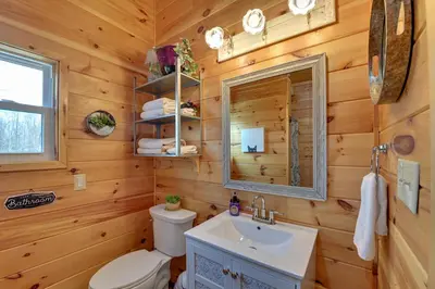 a bathroom with a toilet and a sink and a mirror at Bring a Pet Peaceful Frenchburg Cabin on 1 Acre in Frenchburg