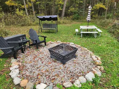 a fire pit with two chairs and a picnic table at Bunny Bungalow Romantic Getaway in a Spacious Geodome in New Straitsville