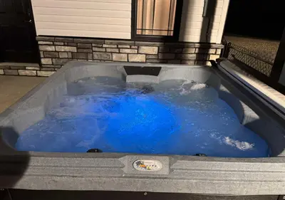 a jacuzzi tub with blue water in it at Country Cornerstone Retreat - Game Room, Theater, Hot Tub, Massage Chairs, Gym, Grill, Sauna, Fire Pit in Hillsboro