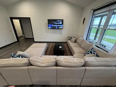 a living room with a large couch and a tv at Country Cornerstone Retreat - Game Room, Theater, Hot Tub, Massage Chairs, Gym, Grill, Sauna, Fire Pit in Hillsboro