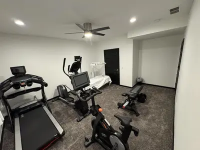 a room with several exercise bikes and a bed at Country Cornerstone Retreat - Game Room, Theater, Hot Tub, Massage Chairs, Gym, Grill, Sauna, Fire Pit in Hillsboro