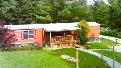 a small orange house with a porch and a yard at 2 Bedroom Logan Ohio Hot Tub in Logan