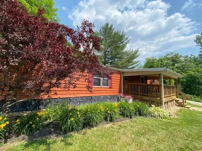 a small orange house with a porch in a yard at 2 Bedroom Logan Ohio Hot Tub in Logan