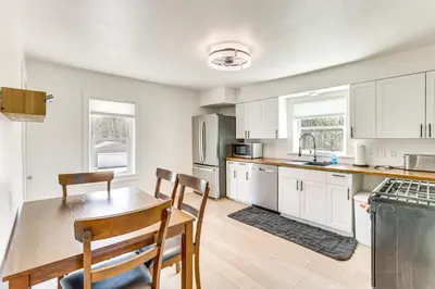 a kitchen with white cabinets and a table and chairs at 3 Mi to Downtown Youngstown Apt with Deck! in Youngstown