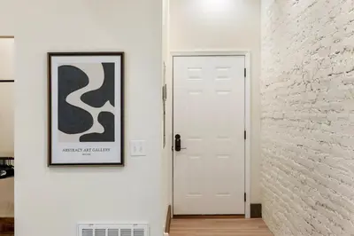 a hallway with a white door and a picture on the wall at Modern Loft-Style Retreat Near Blenko Glass in Milton, WV in Hurricane