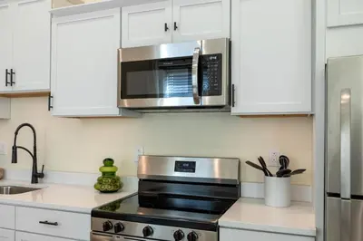 a kitchen with white cabinets and a stainless steel microwave at Modern Loft-Style Retreat Near Blenko Glass in Milton, WV in Hurricane