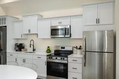 a kitchen with white cabinets and a stainless steel refrigerator at Modern Loft-Style Retreat Near Blenko Glass in Milton, WV in Hurricane