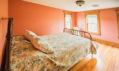 a bedroom with orange walls and a bed with pillows at Nature Valley Farm- 2BD/1BA on private 53 acres in North Lawrence